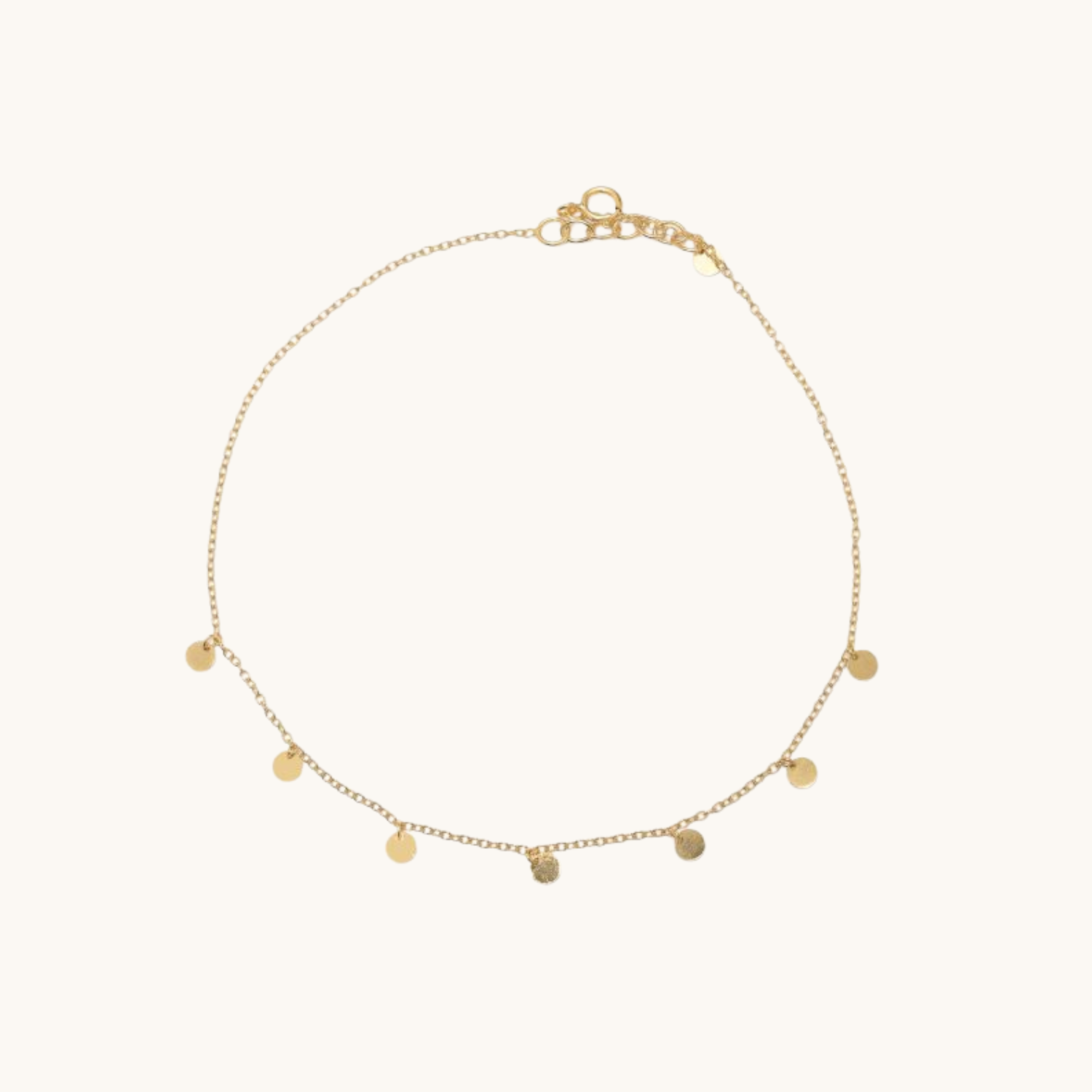 Gold anklet with small round pendants on a white background