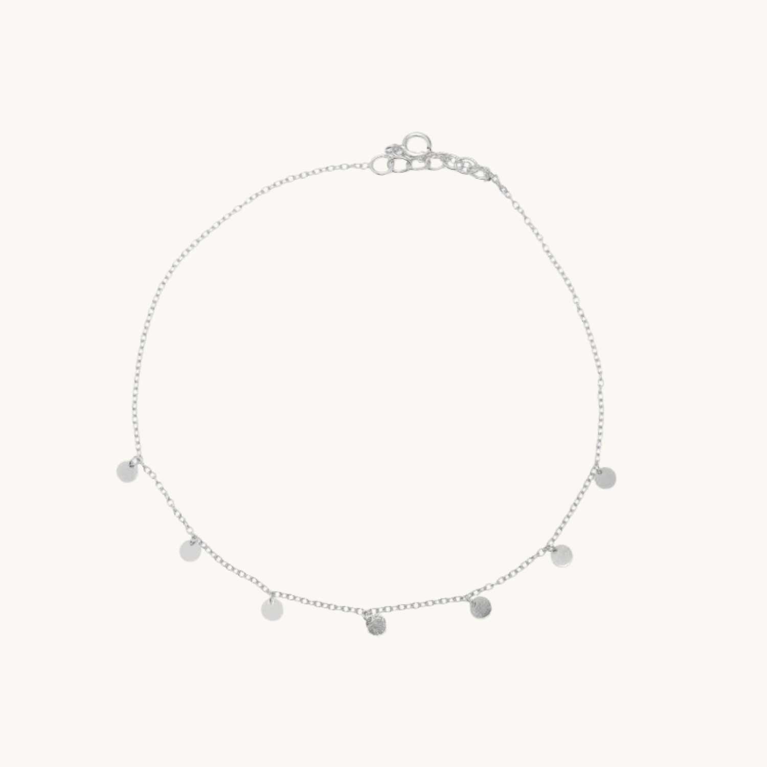 Silver anklet with small round pendants on a white background