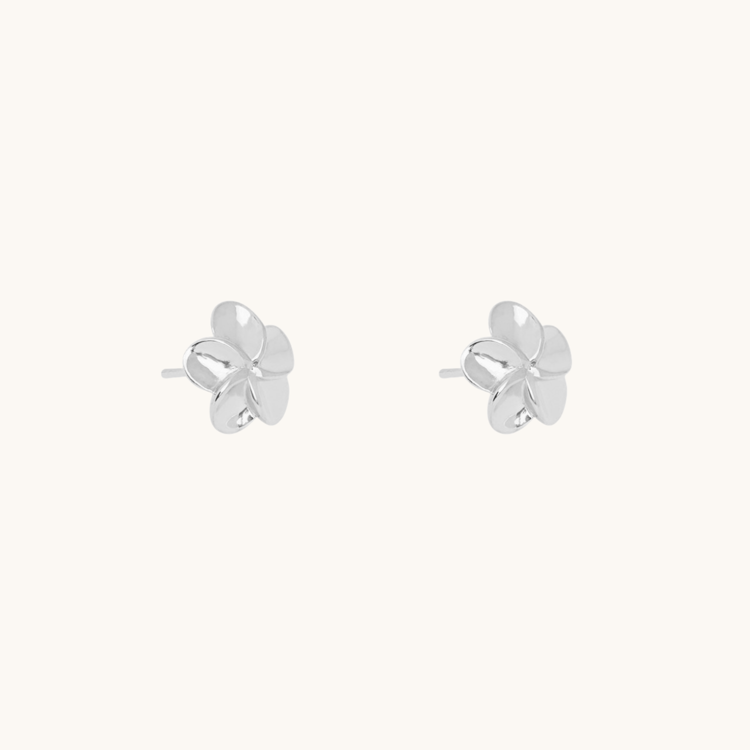 Silver flower earrings on a cream background