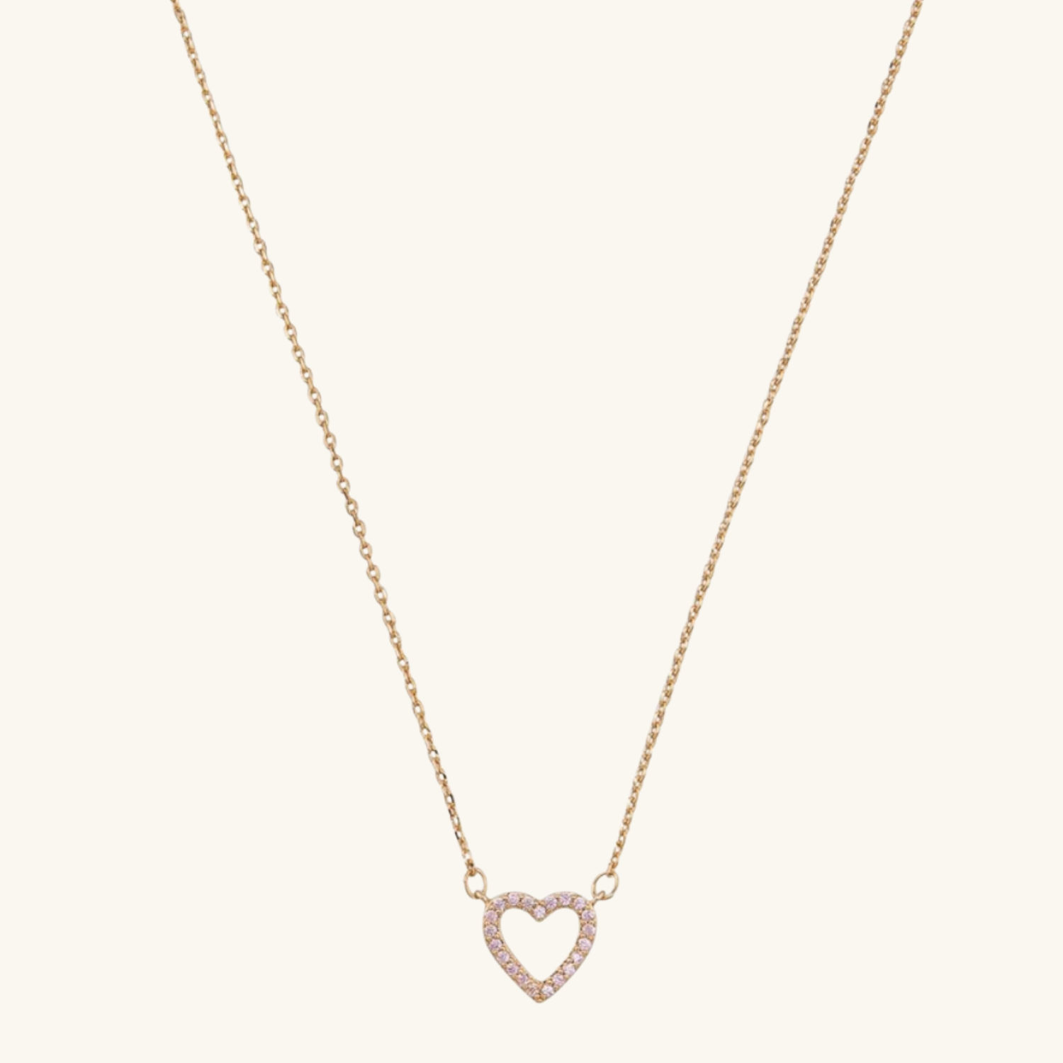Heart-shaped necklace with rose gold chain on a light beige background