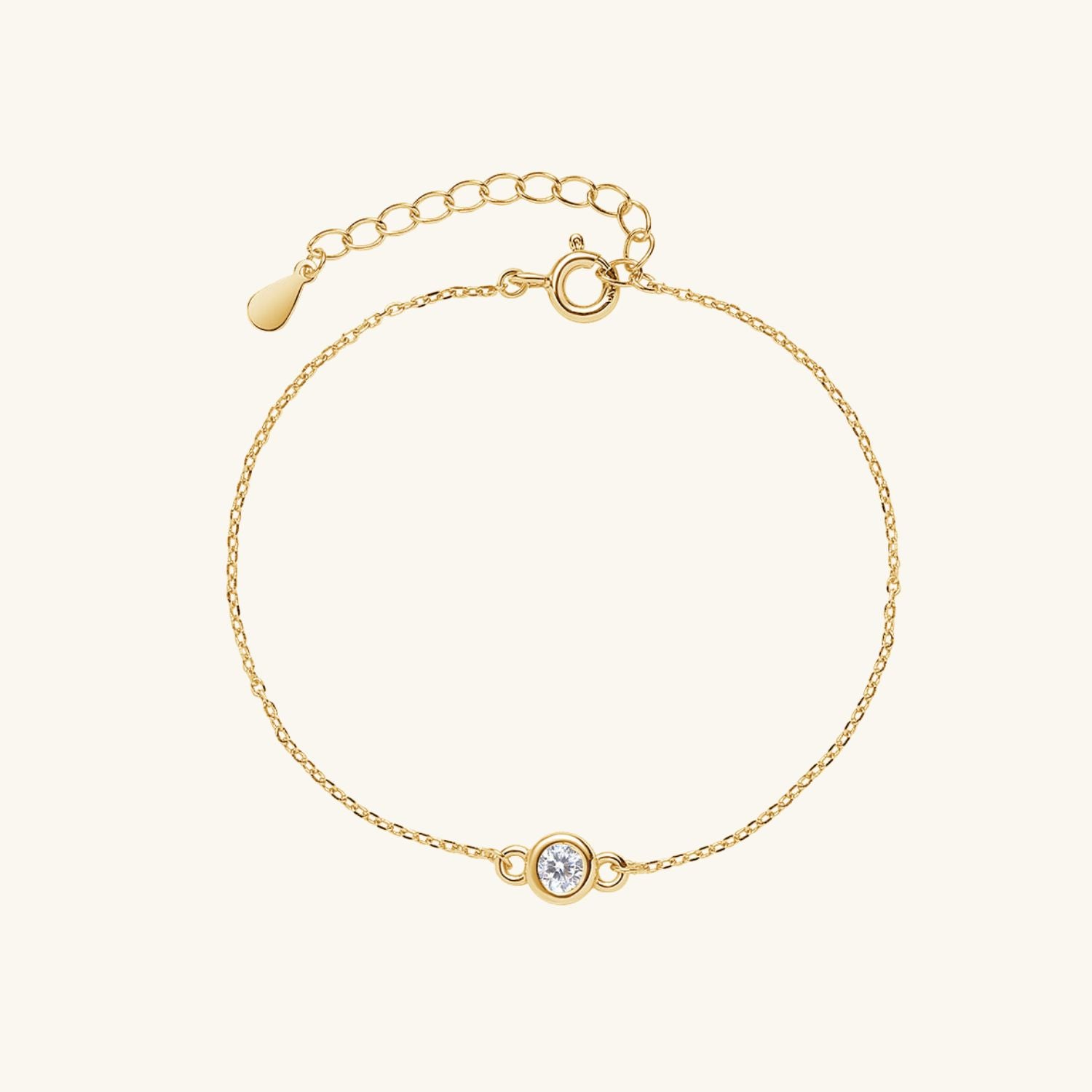 Gold bracelet with a small zircon on a light beige background