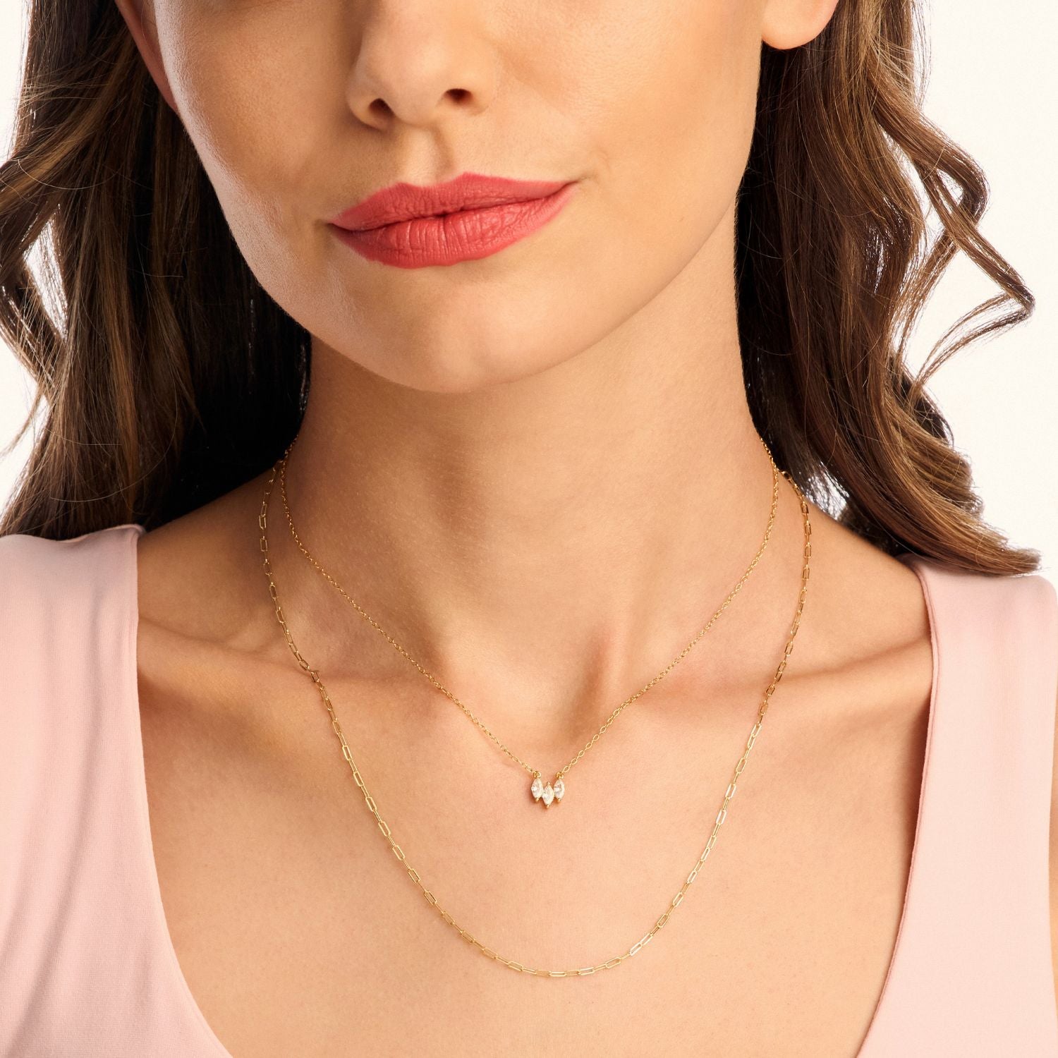 Model wearing a long gold paperclip necklace layered with a shorter necklace, showcasing a chic, modern, and stylish stacked look