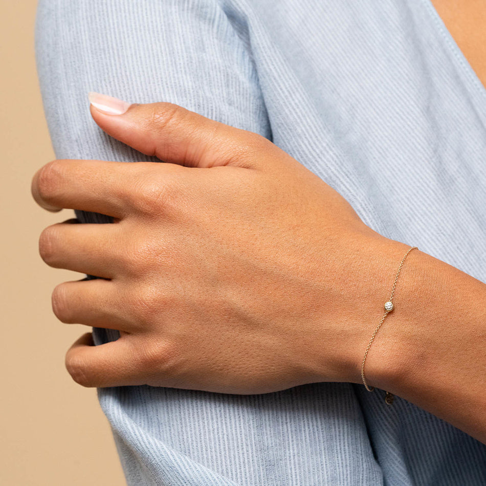 Hand wearing delicate zircon bracelet on a neutral background