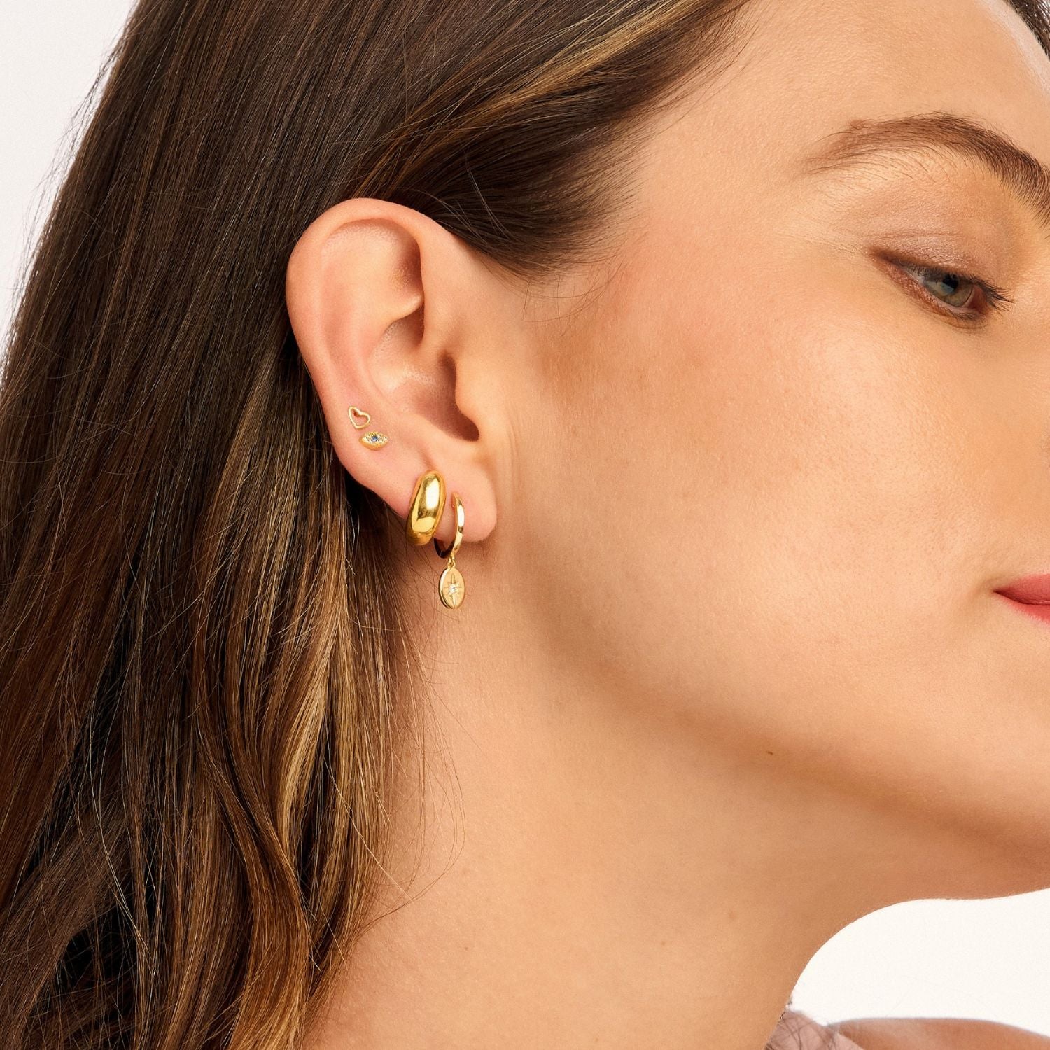 Model wearing Vesper Huggie Earrings, showcasing their gold-plated oval drop and delicate star design for a chic, celestial-inspired look