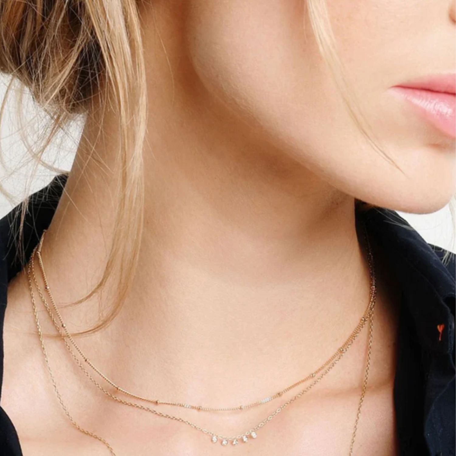 Close-up of a woman wearing delicate gold necklace with zircon drops