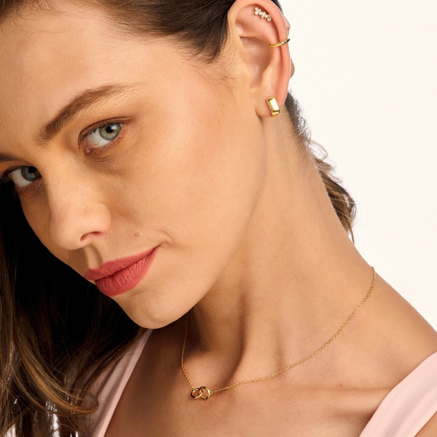 Model wearing gold icon Huggie earrings in a square cube shape, showcasing a modern and chic look