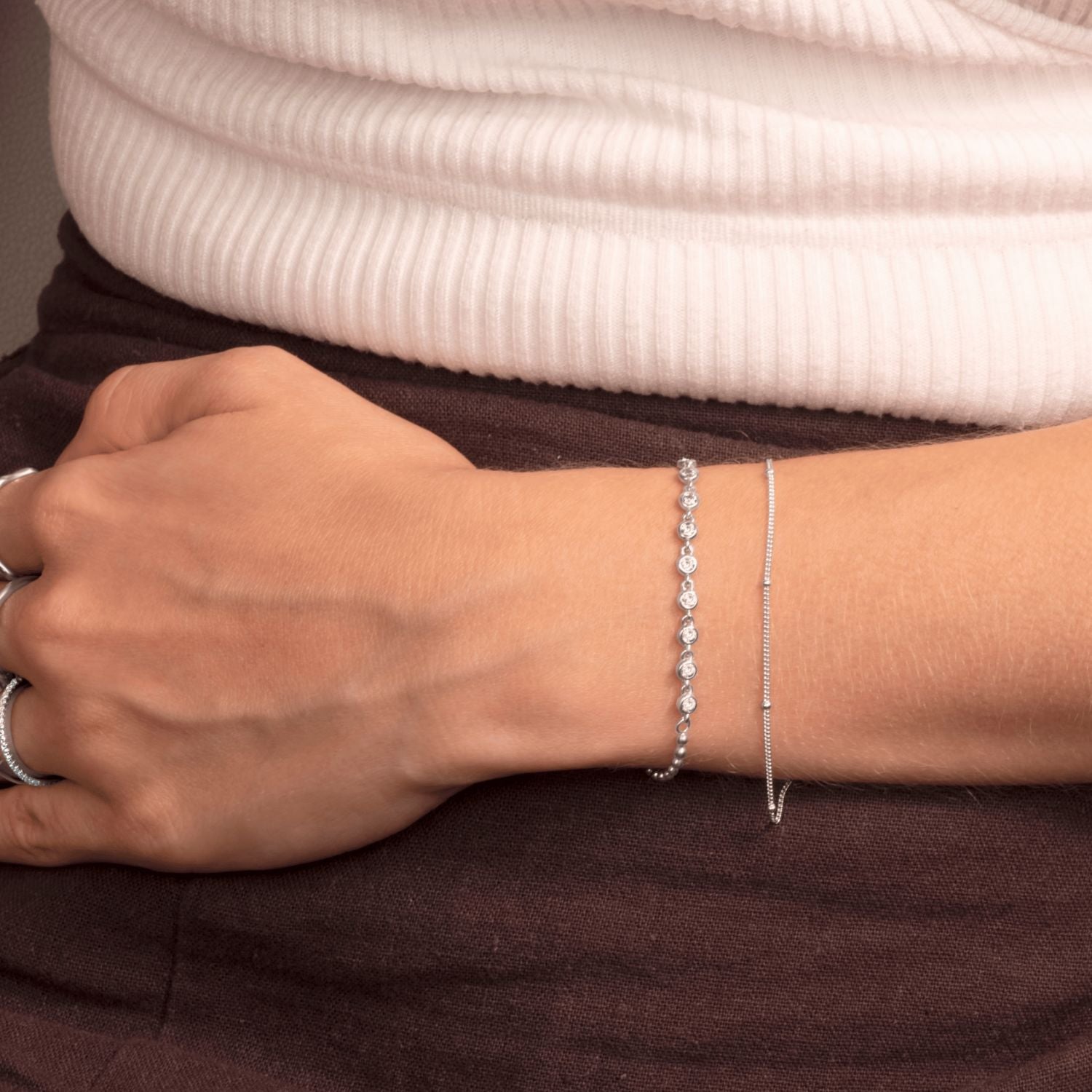 Model wearing silver bracelet with rhinestones and polished ball accents – elegant, minimalist style.