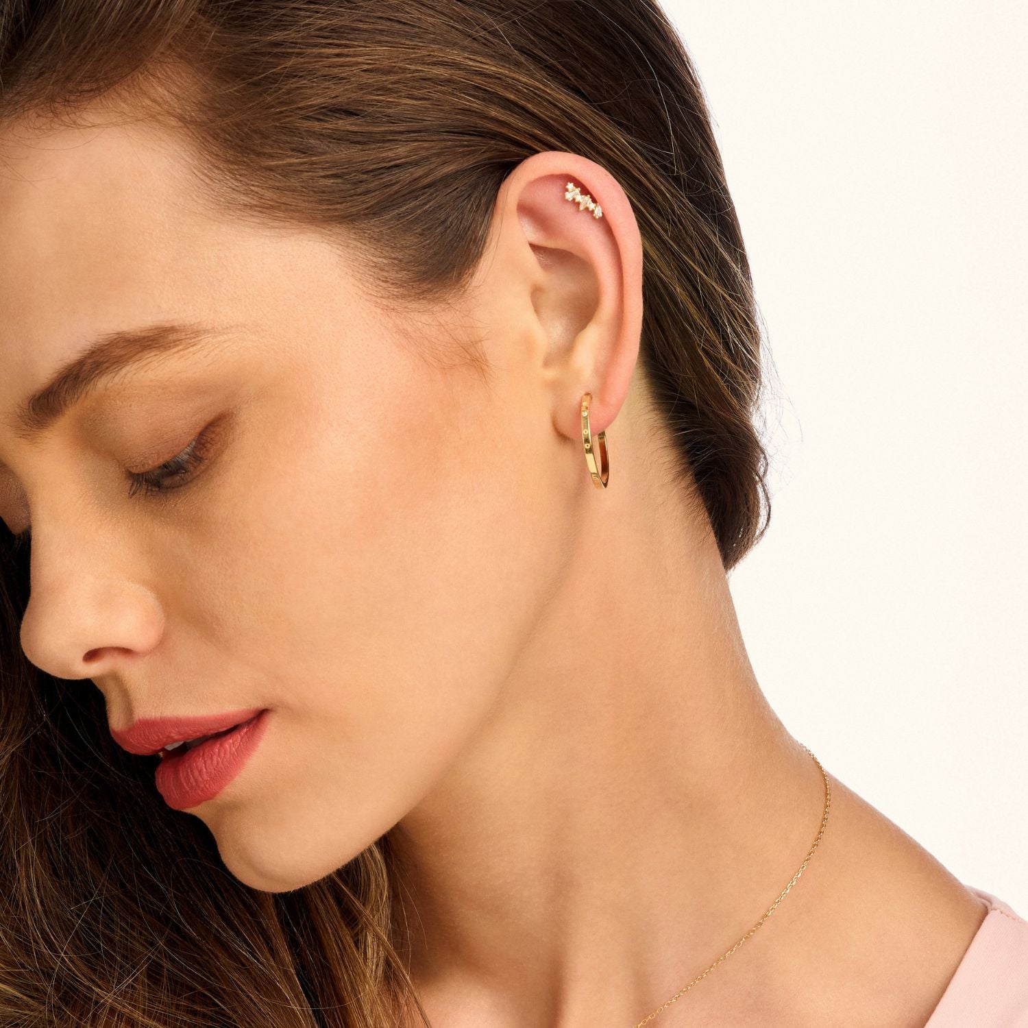 Model wearing gold decorative hoop earrings, showcasing their intricate design and elegant shine. Perfect for a chic statement or stylish stacking.