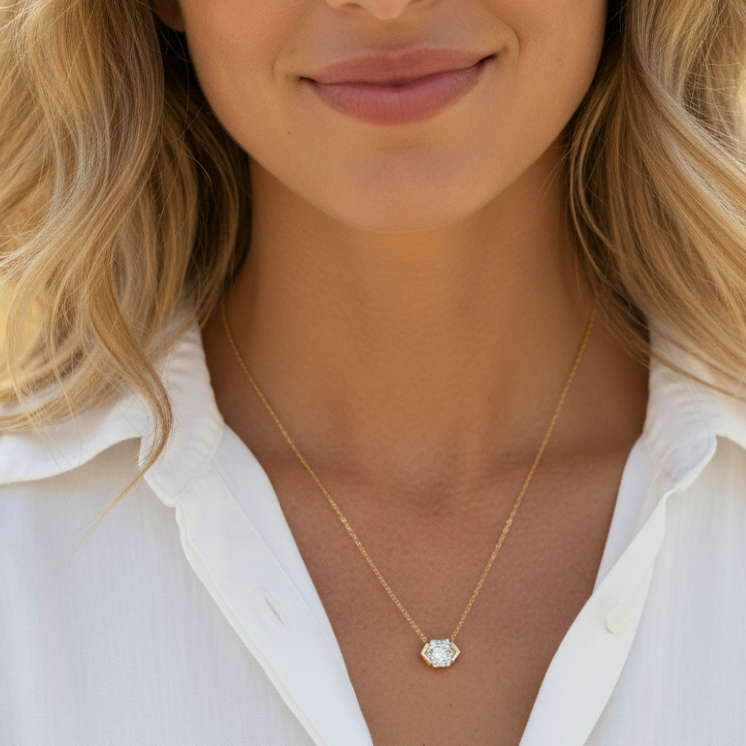 Close-up of a woman wearing a gold necklace with a white shirt.