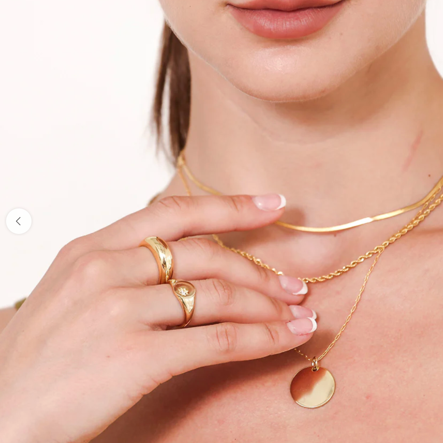 Gold jewelry including necklaces and rings on a person's hand and neck.