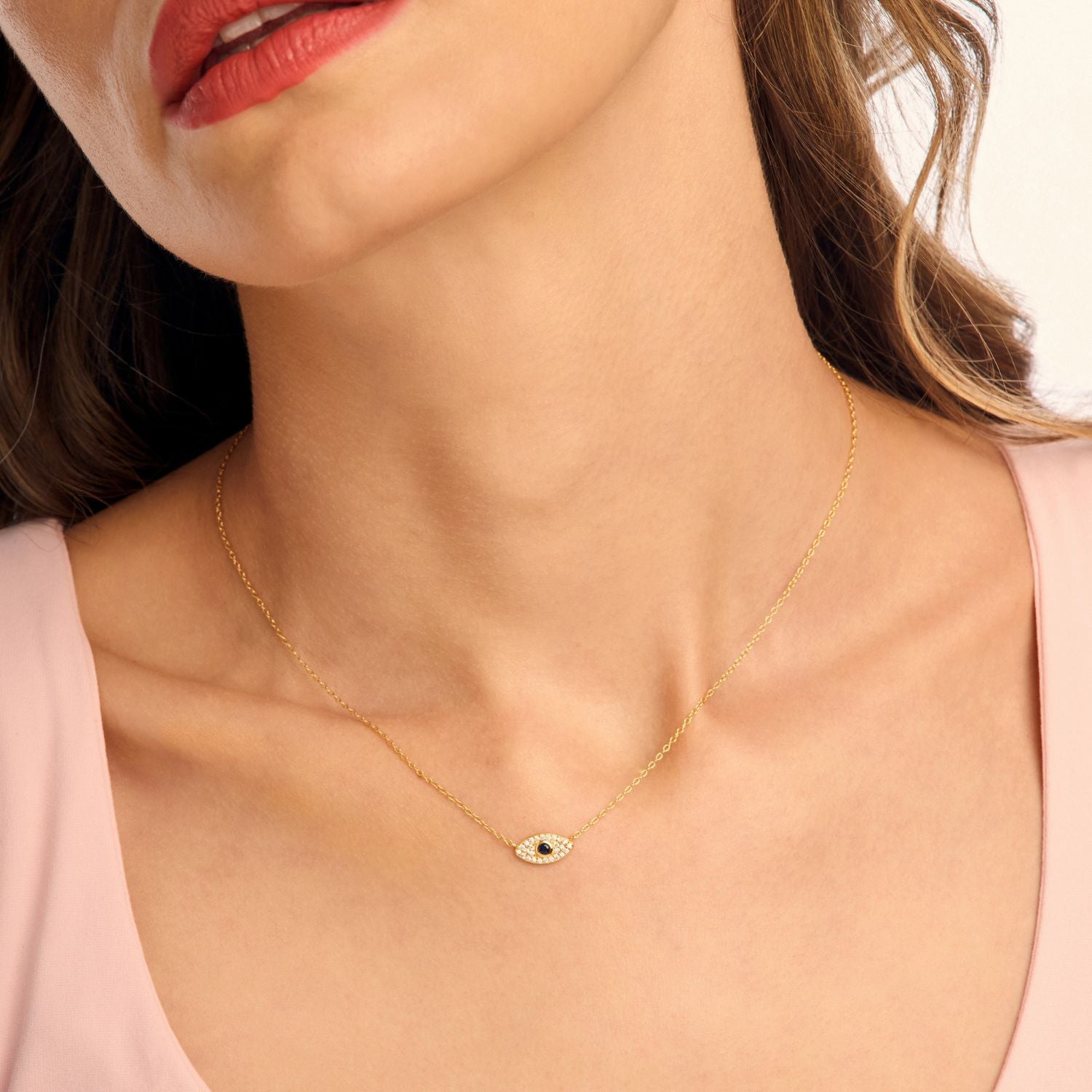 Model wearing a gold evil eye necklace on a delicate chain, showcasing its symbolic charm for protection and elegant everyday style