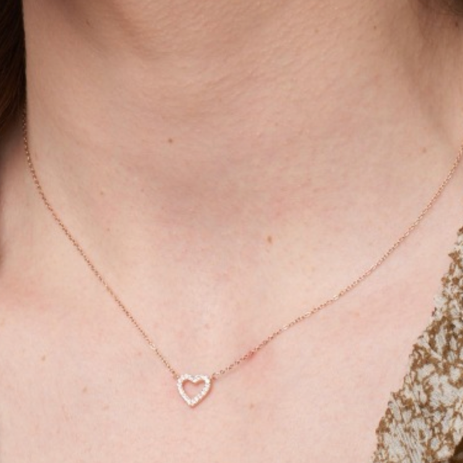 Rose gold heart-shaped necklace on a person's neck