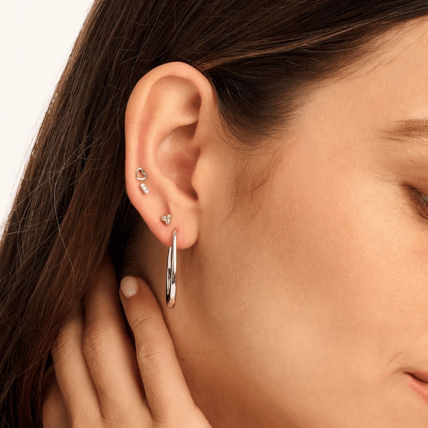 Model wearing silver Halo Hoop earrings, showcasing their sleek 2.5cm drop and high-shine finish for a modern yet timeless look