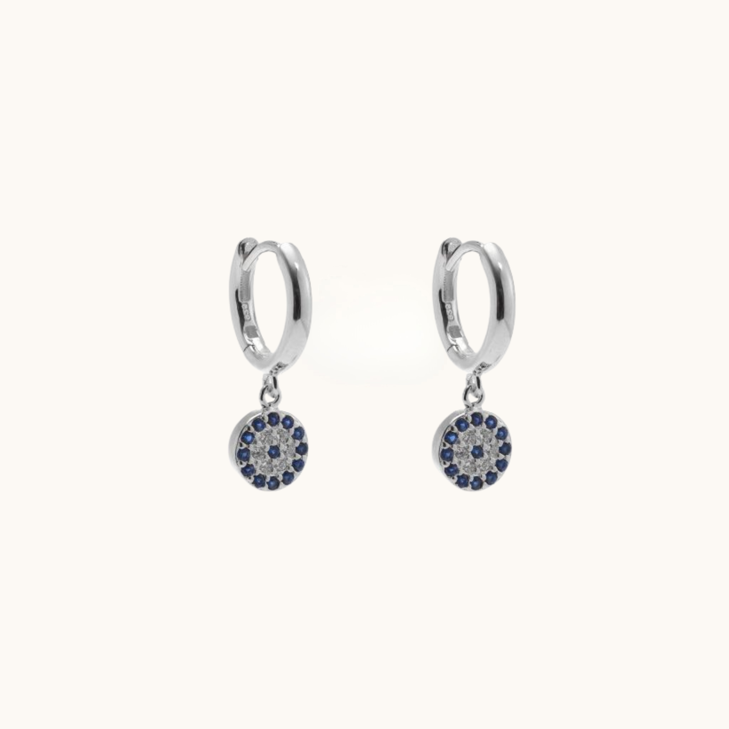 Pair of silver hoop earrings with circular charms featuring blue stones on a white background