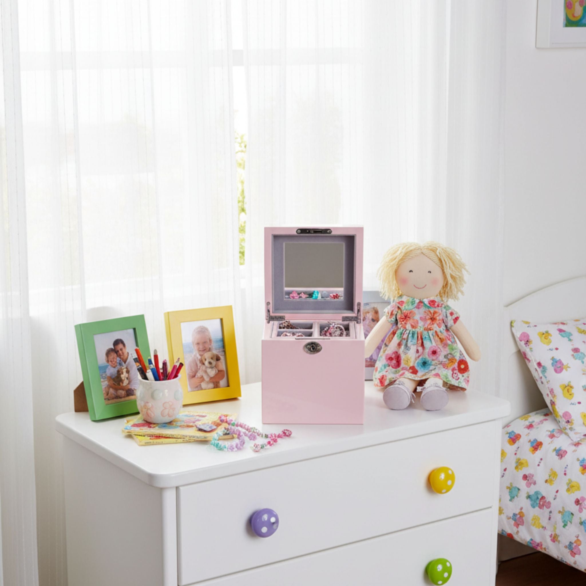 Children's room with a white dresser, toys, and decorative items.
