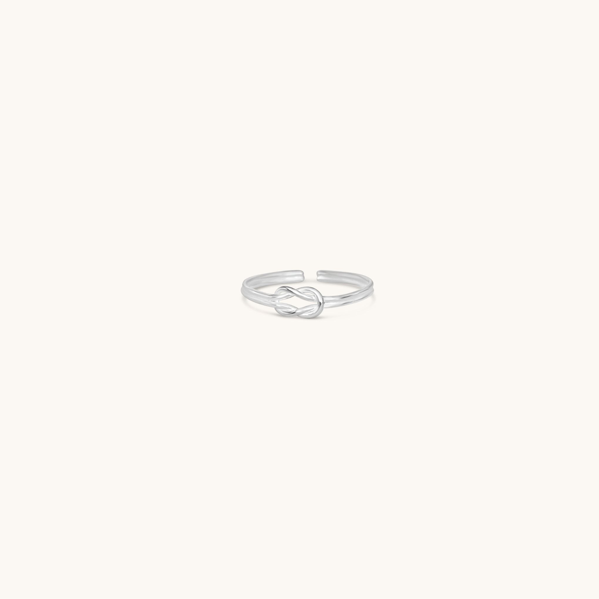 Silver toe ring with a knot design on a white background