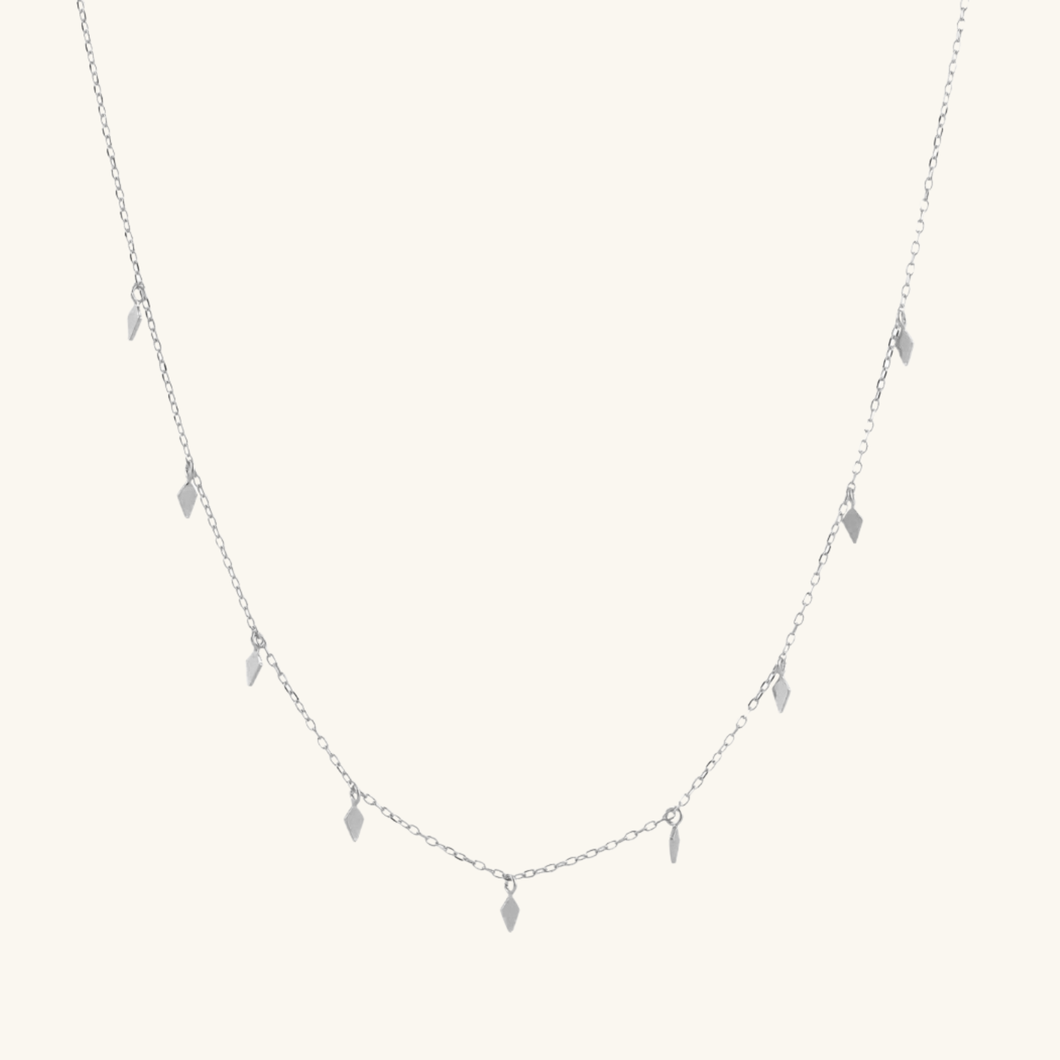 Delicate necklace with small pendant on a light cream background