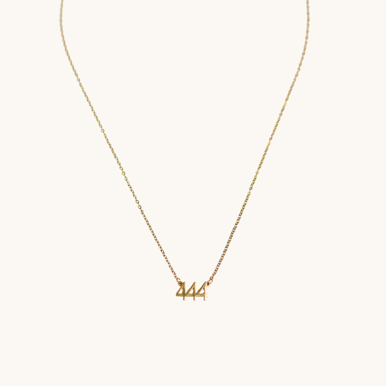 Gold necklace with '444' pendant on a white background
