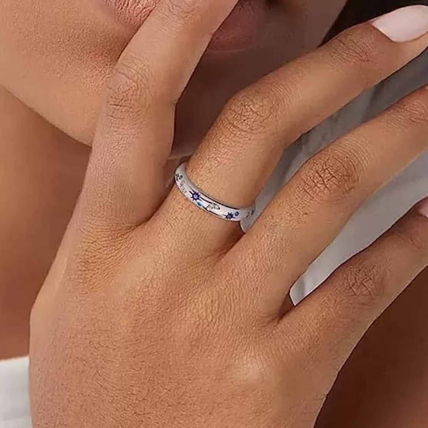 Close-up of a hand wearing a silver ring with blue stones.