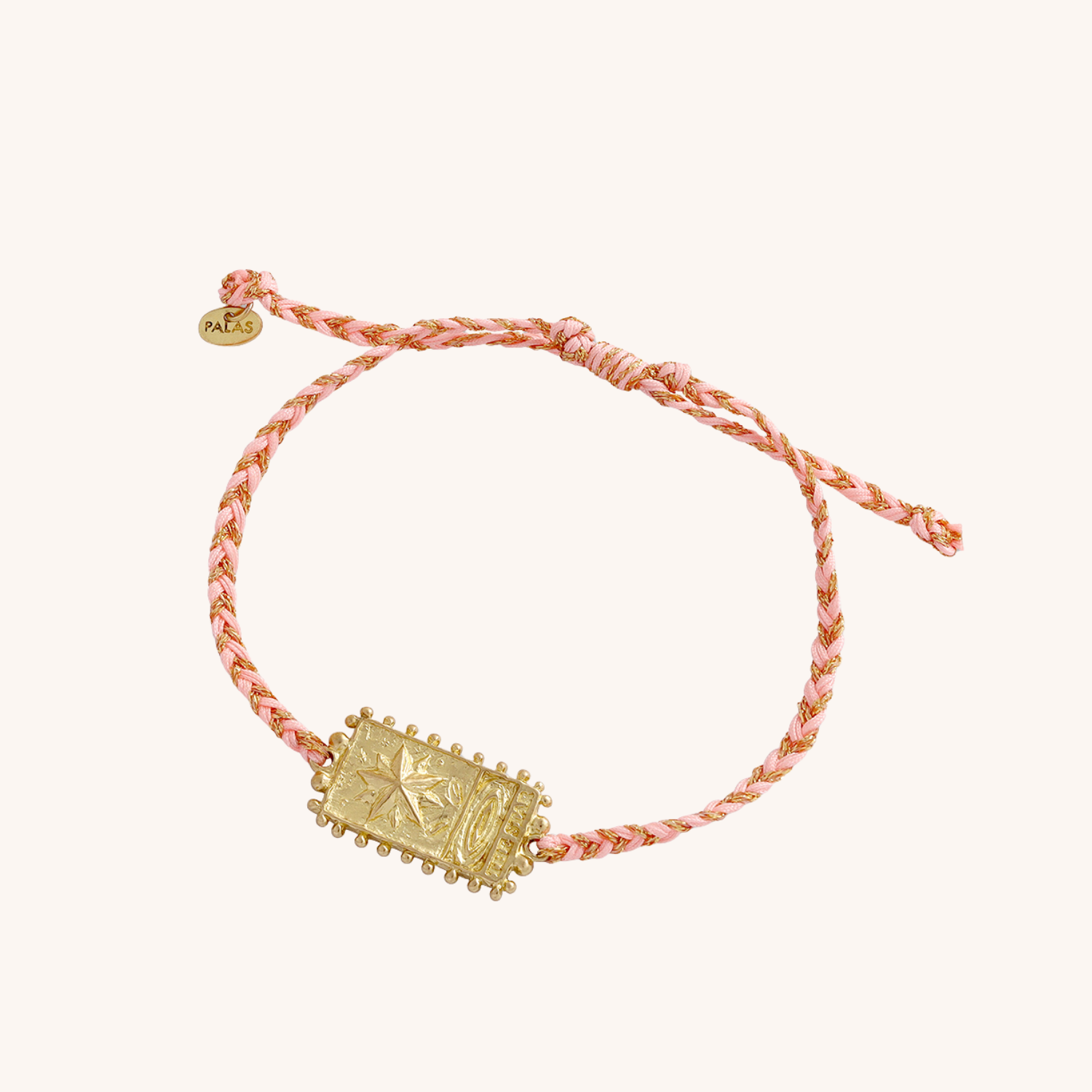 Bracelet with gold emblem and pink cord on a white background