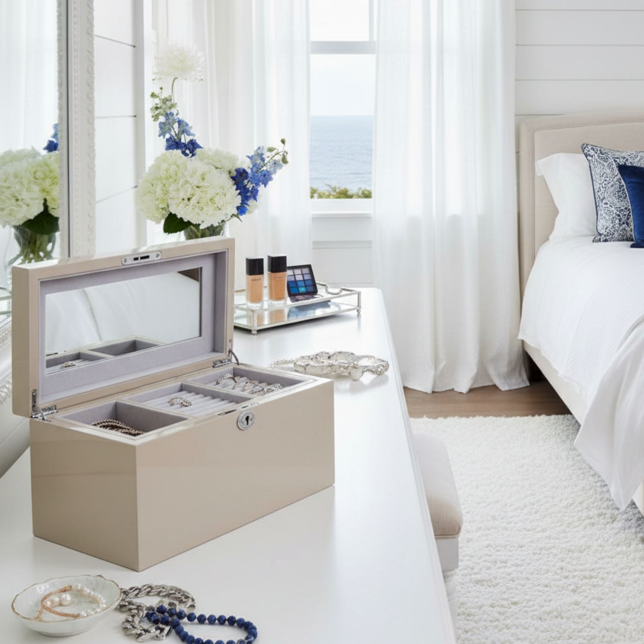 Jewelry box on a table in a bright bedroom with flowers and jewellery.