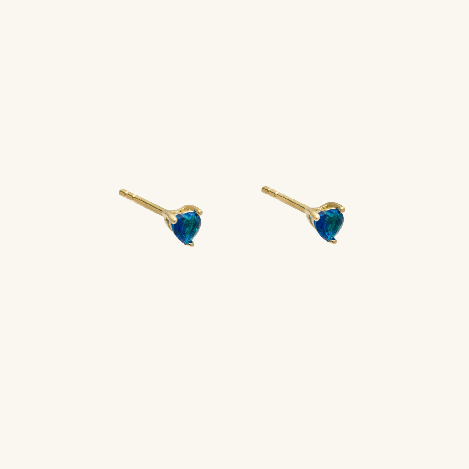 Pair of gold earrings with blue cubic zirconia on a white background