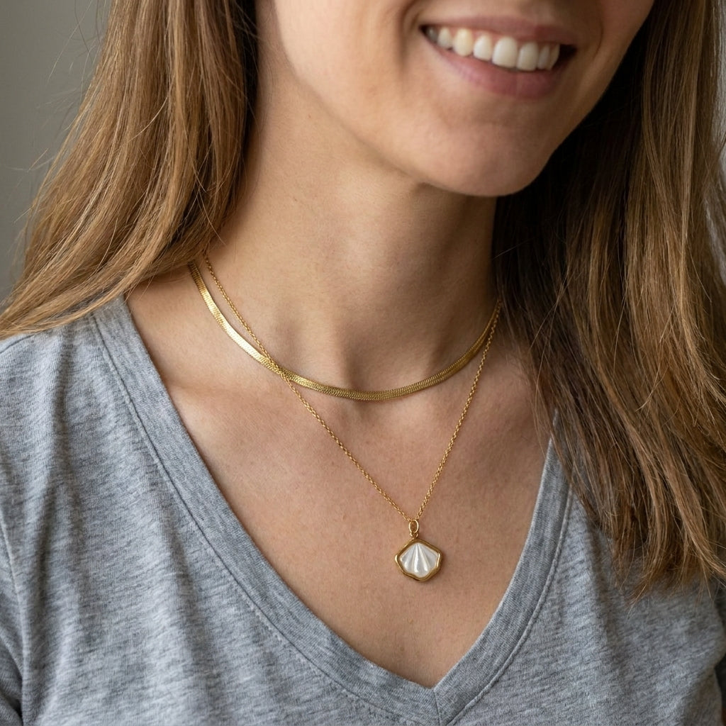 Close up of model wearing shell necklace stacked with snake chain
