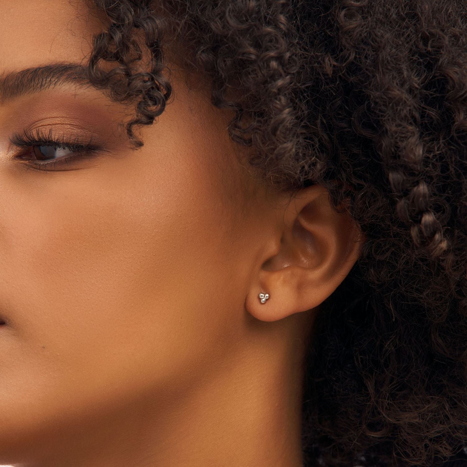 Model wearing silver three-ball cluster earrings, showcasing their sleek, minimalist design. A versatile and elegant accessory for any occasion