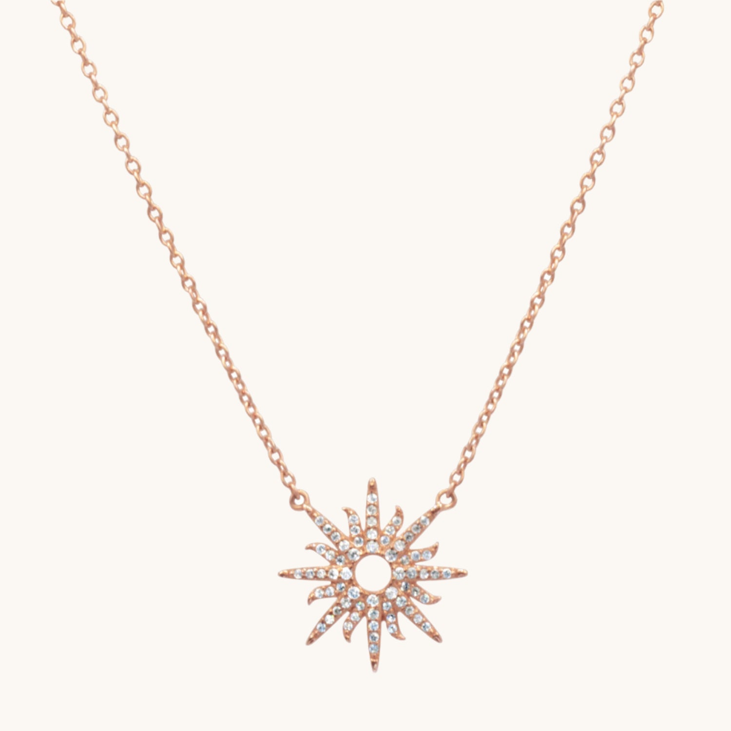 Rose gold plated Sunburst necklace  flat lay image on cream background