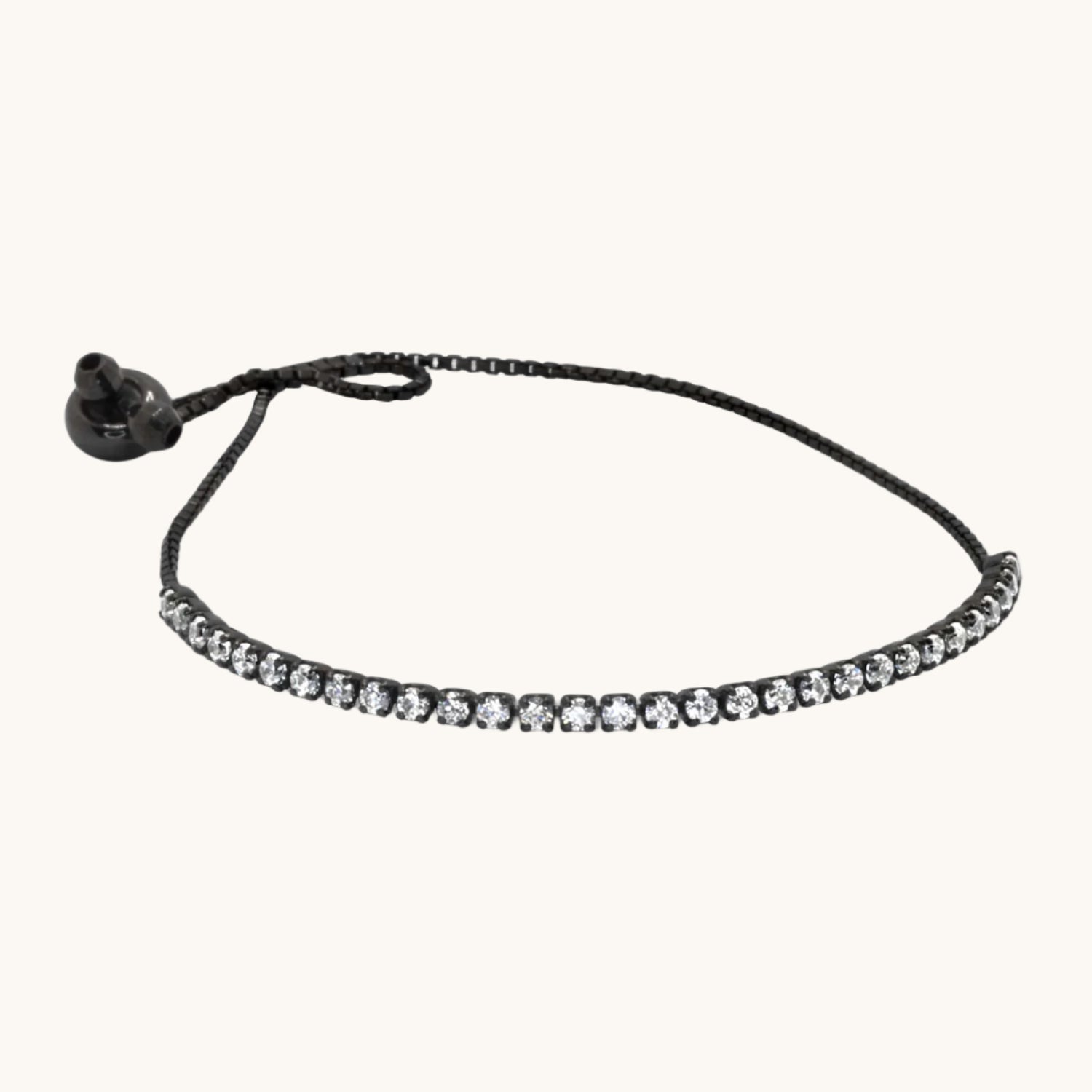 Flat lay image of a cubic zirconia tennis bracelet with a black chain bracelet, styled on a soft cream background