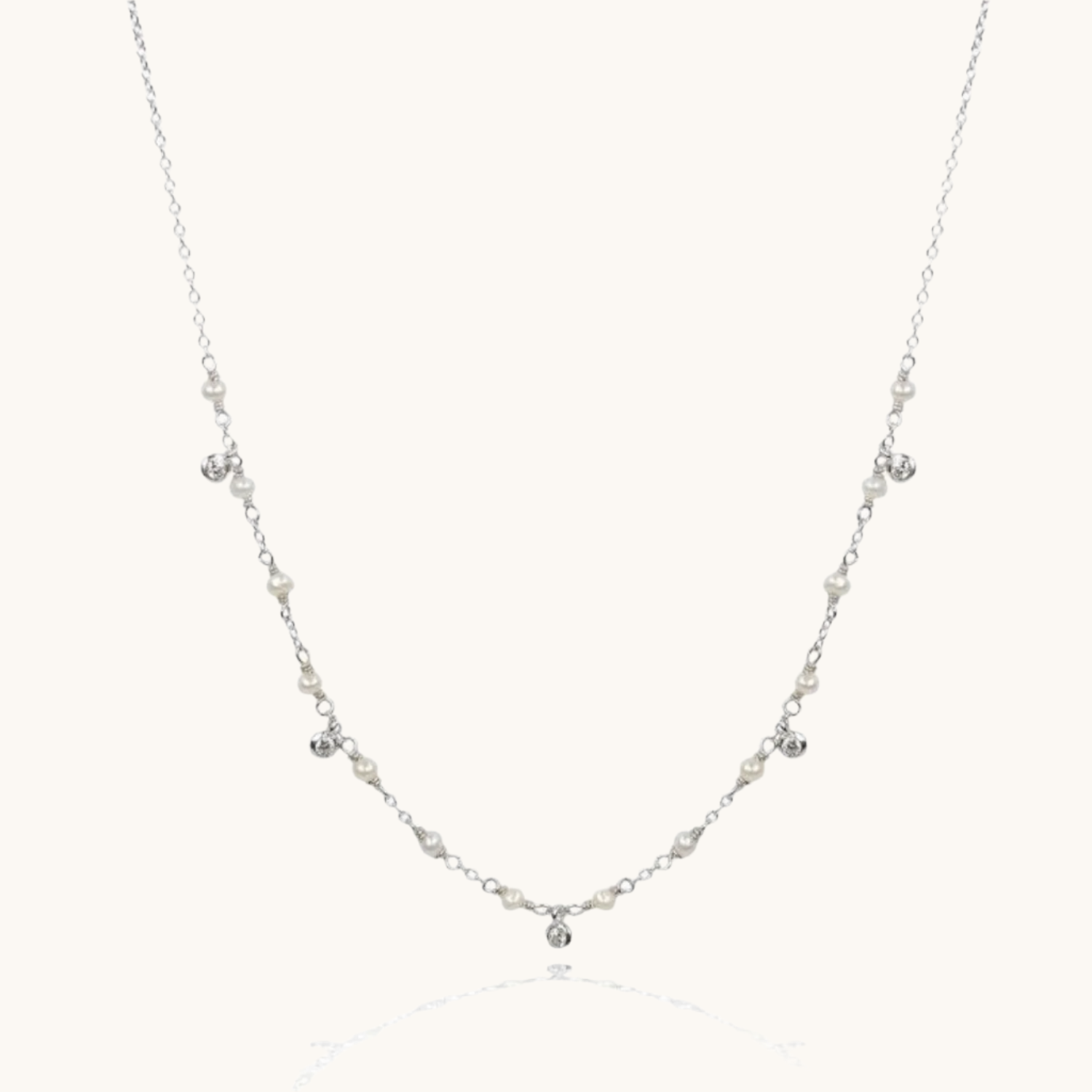 Cubic zirconia and pearl drop sterling silver necklace on cream background