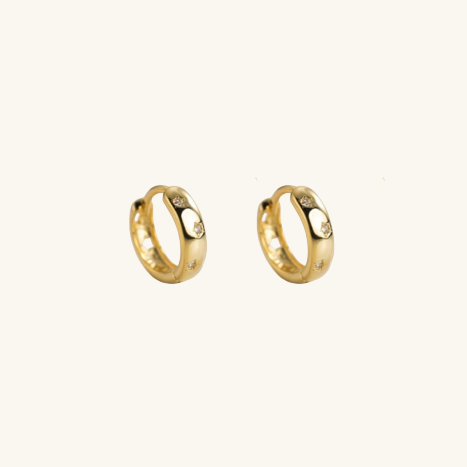 Gold hoop earrings with small star cut-outson a white background