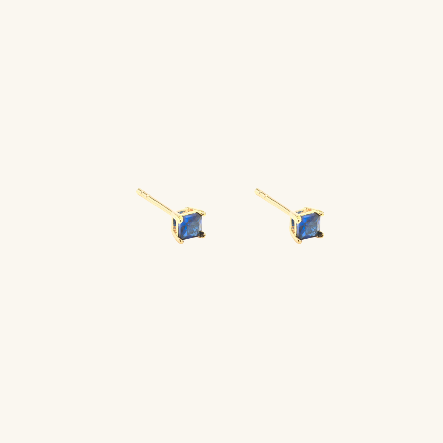 Gold earrings with blue cubic zirconia on a white background
