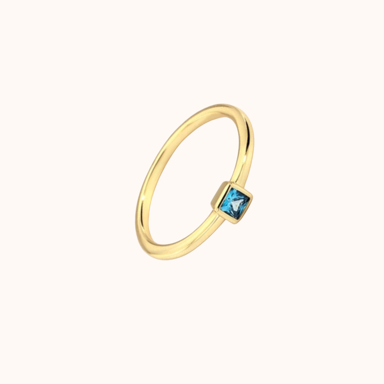 Gold ring with a blue gemstone on a white background