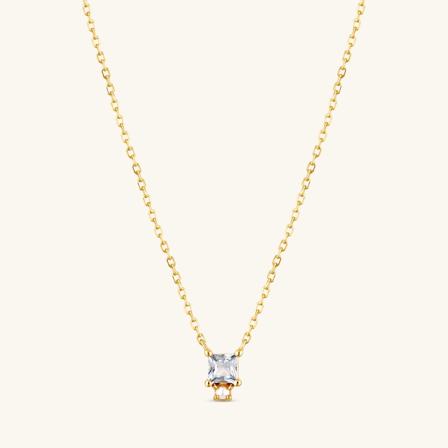 Blue CZ drop necklace with a small fresh water pearl  on a gold chain, featuring an elegant and timeless design