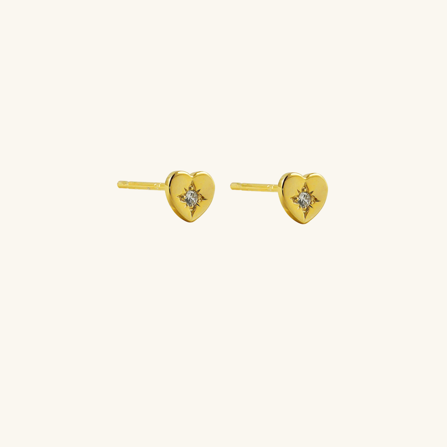 Heart shaped gold plated earrings on a cream background