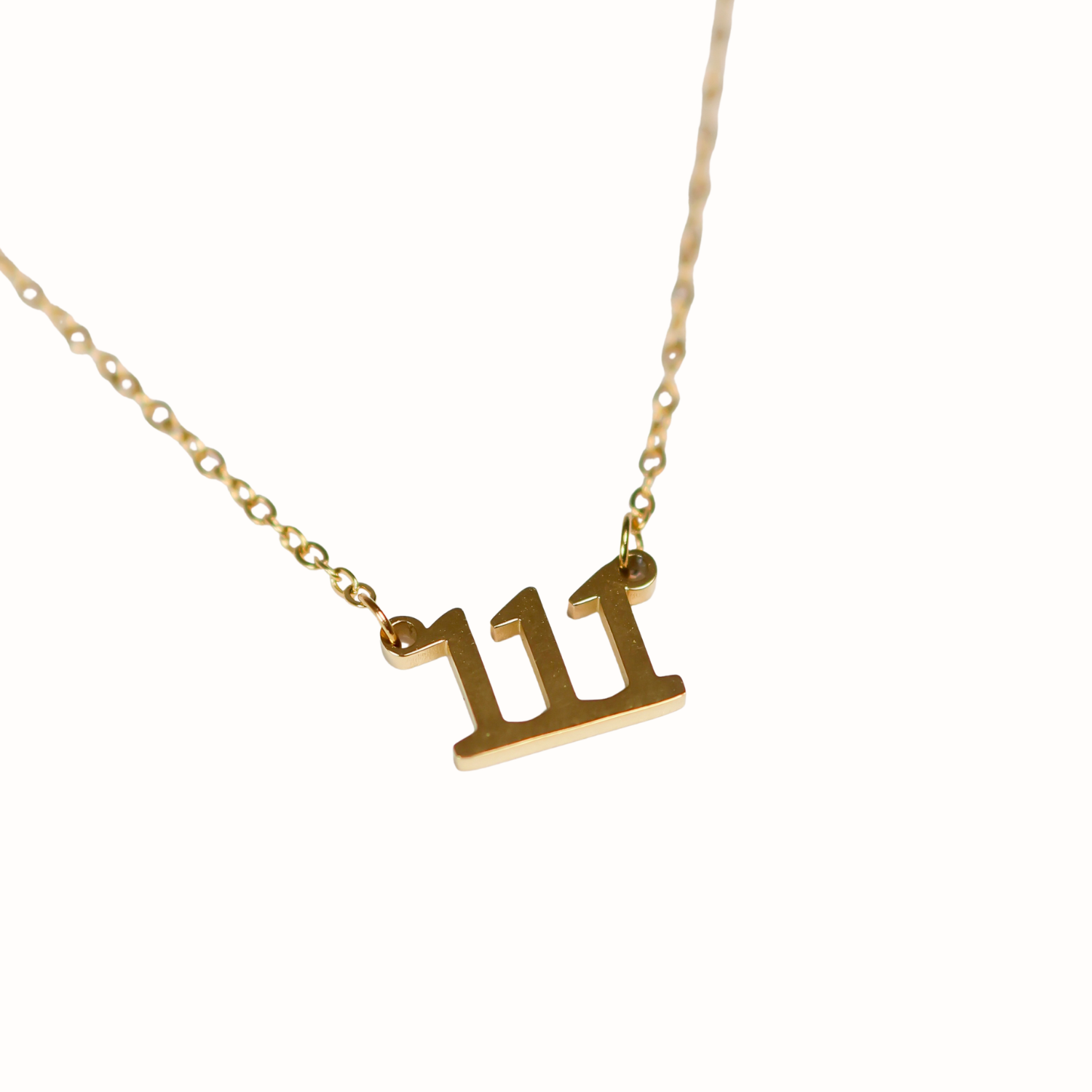 Gold necklace with a number '111' pendant on a white background
