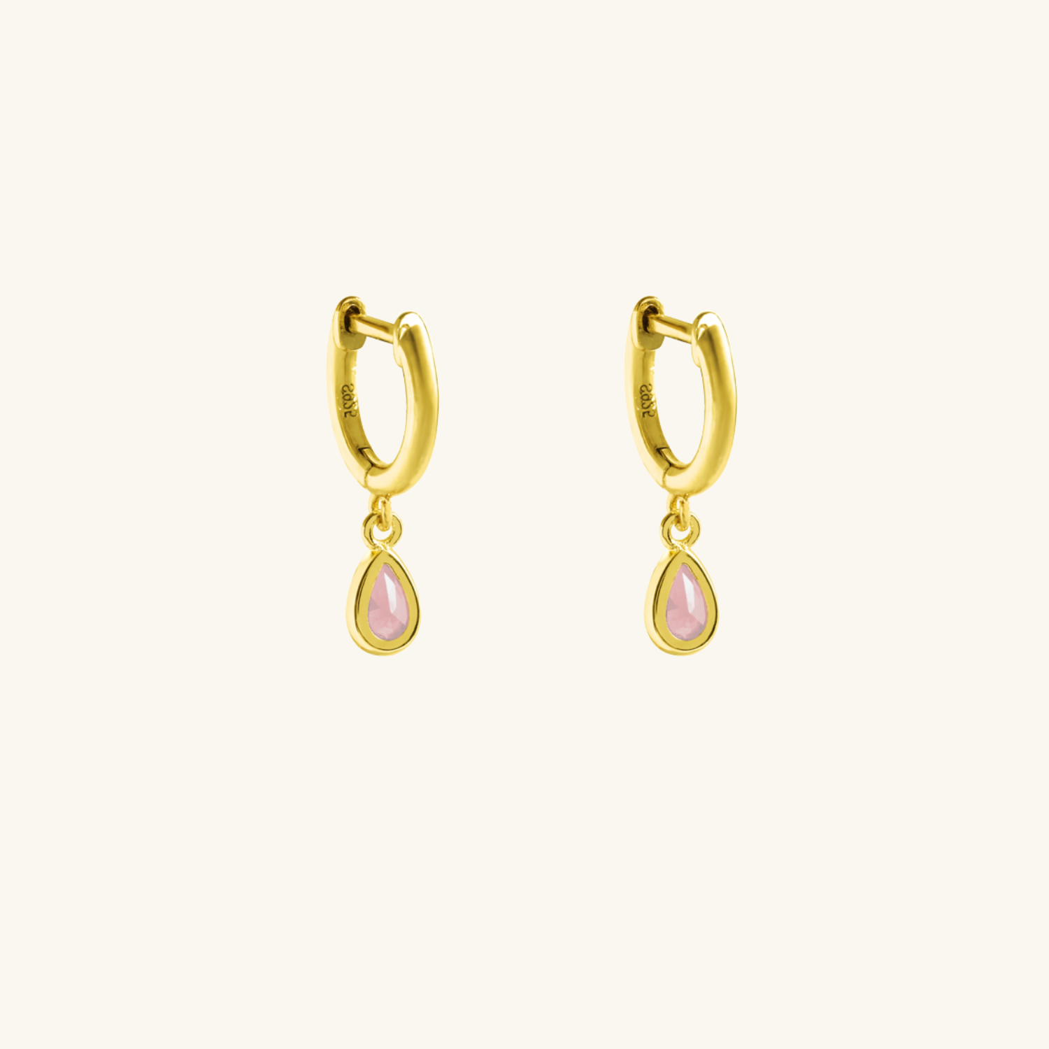 Gold hoop earrings with pink teardrop charms on a white background