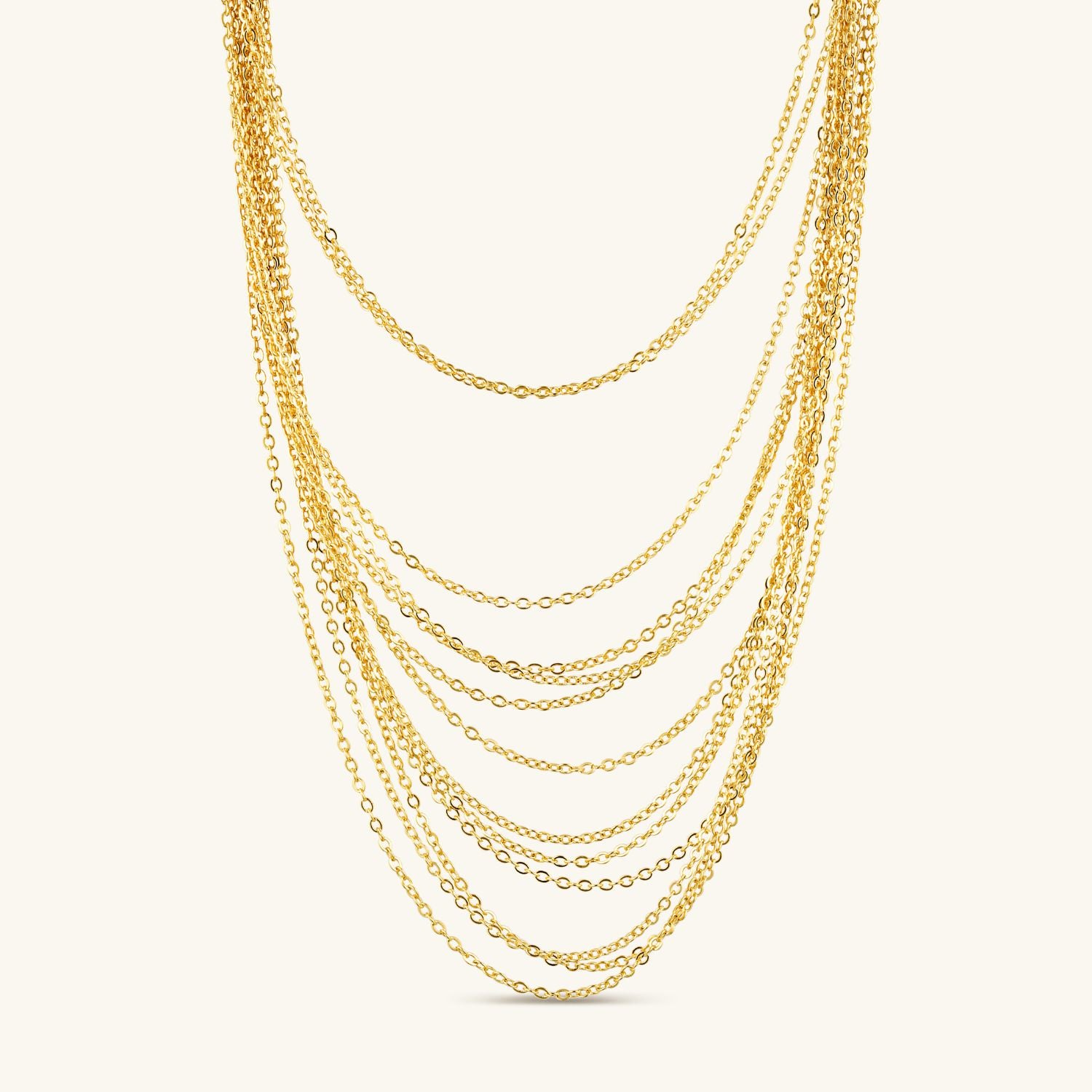 Product shot of a multi-layered necklace featuring multiple gold chains cascading down, creating a stunning layered look against a cream background