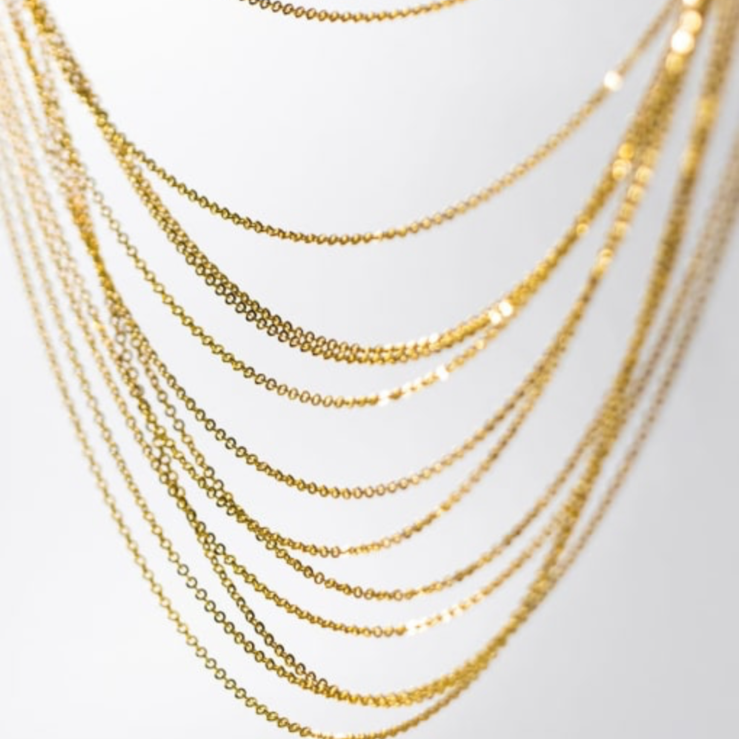 Multiple gold chains stacked on a light gray background