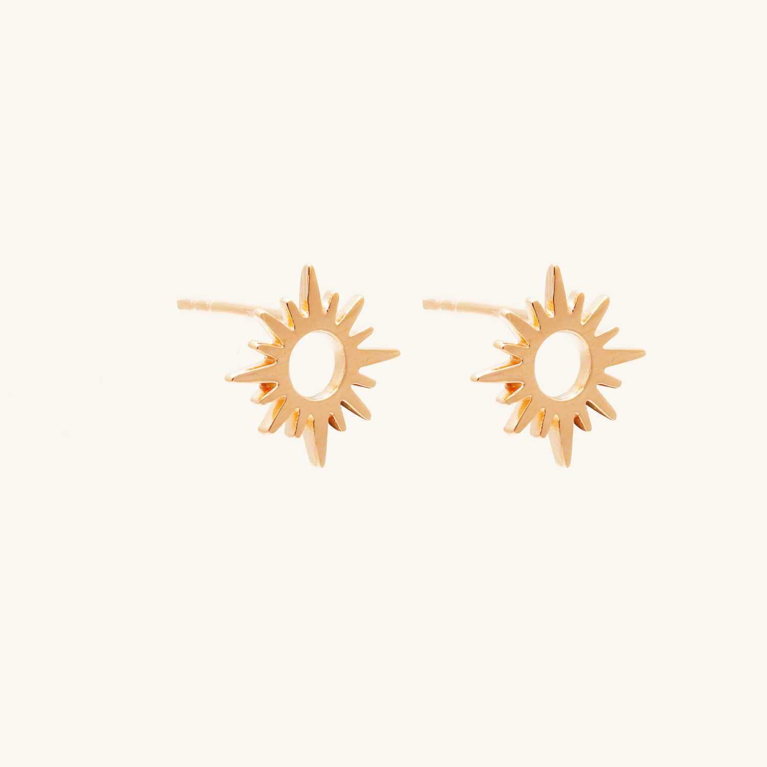 Pair of rose gold sun-shaped earrings on a white background