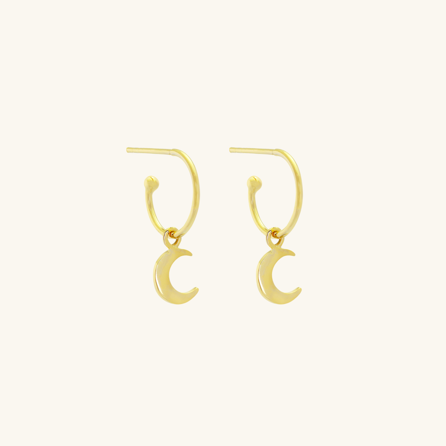 Gold plated crescent moon earrings on a cream background