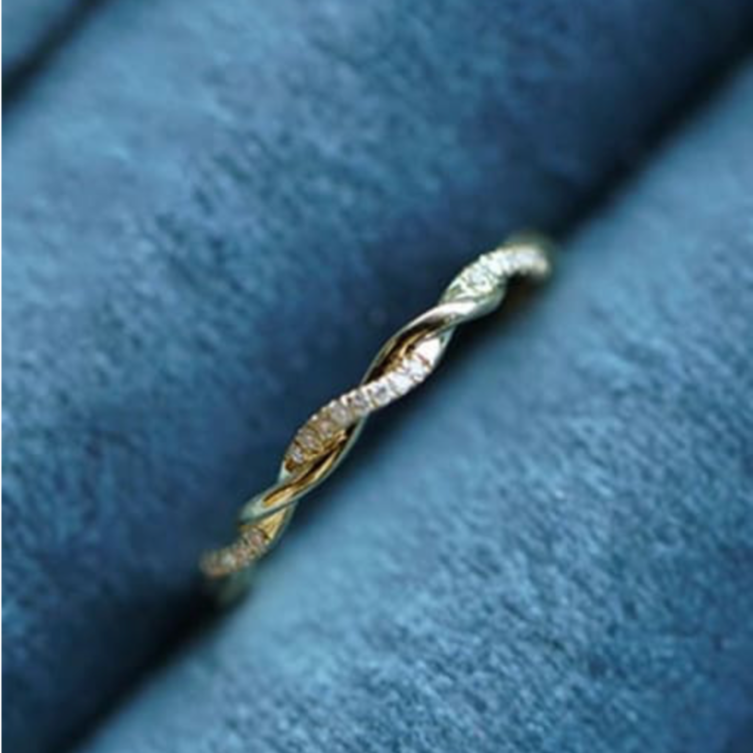 Gold ring with diamonds on a blue fabric background