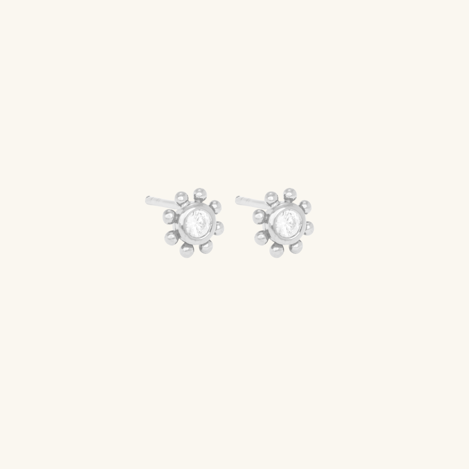 Silver earrings with a central CZ Stone on a cream background