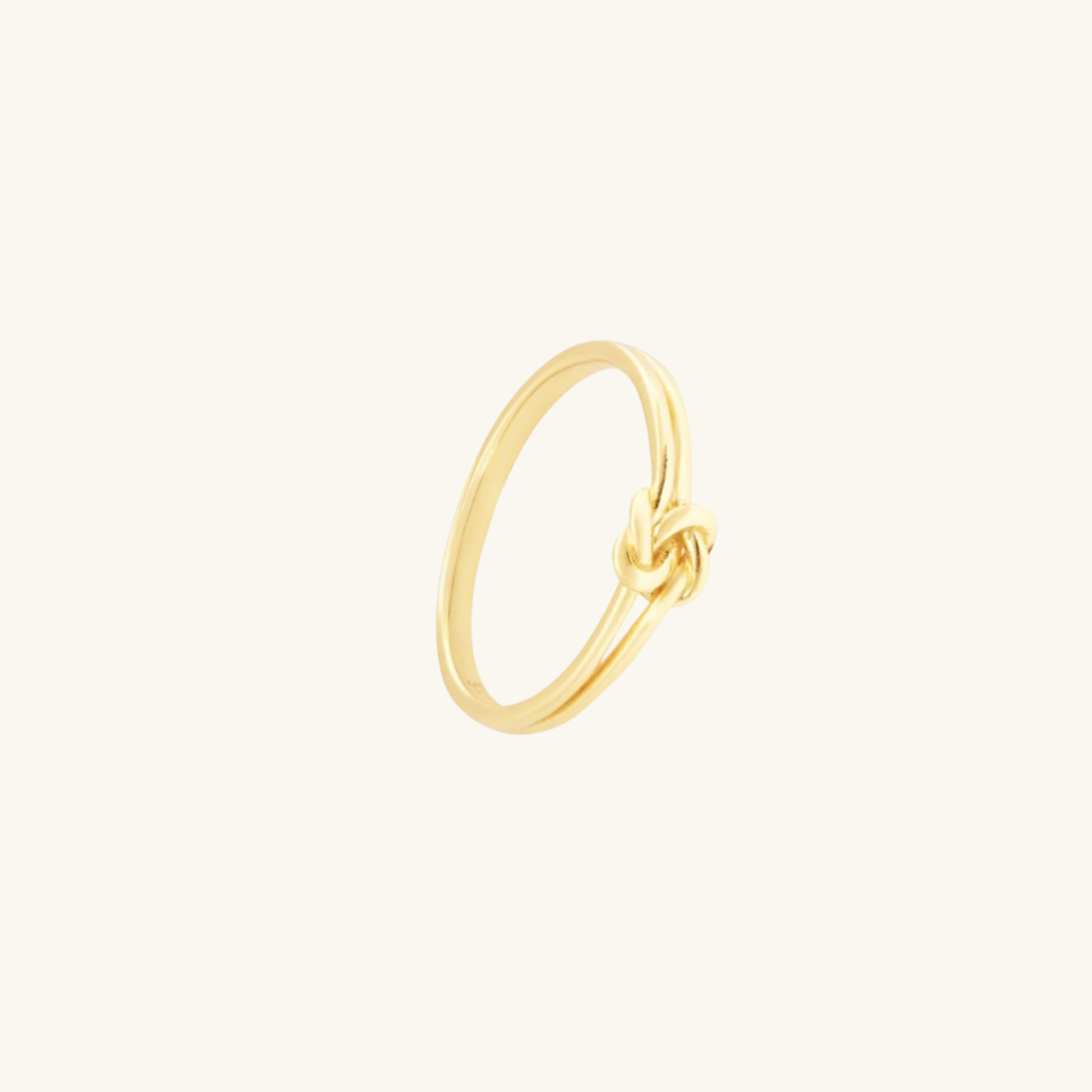 Gold knot ring on a light beige background
