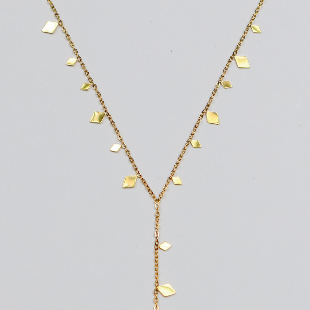 Gold necklace with diamond-shaped pendants on a gray background