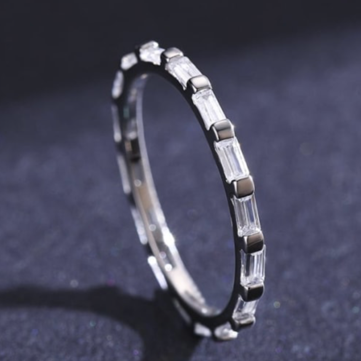 Silver ring with clear stones on a dark textured background