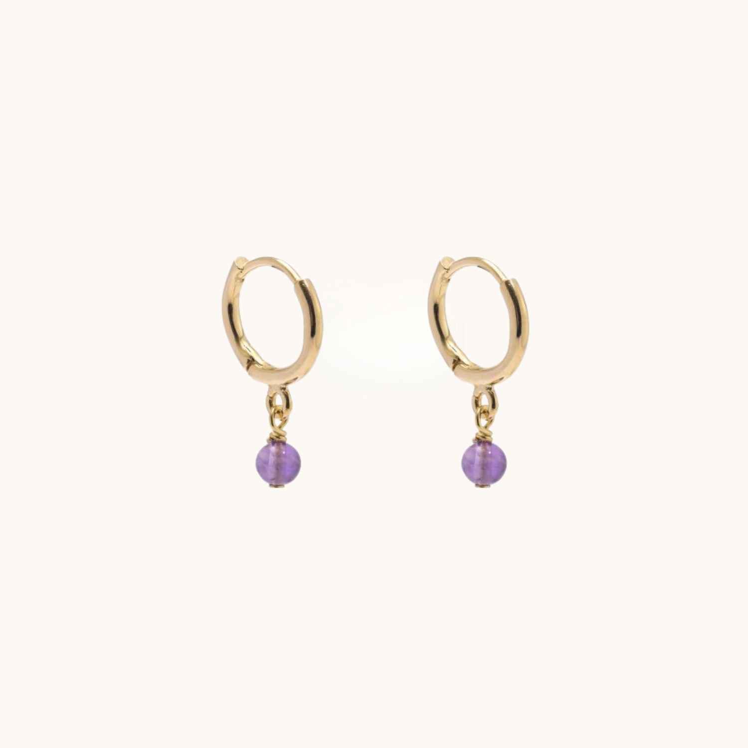 Gold hoop earrings with amethyst on a white background