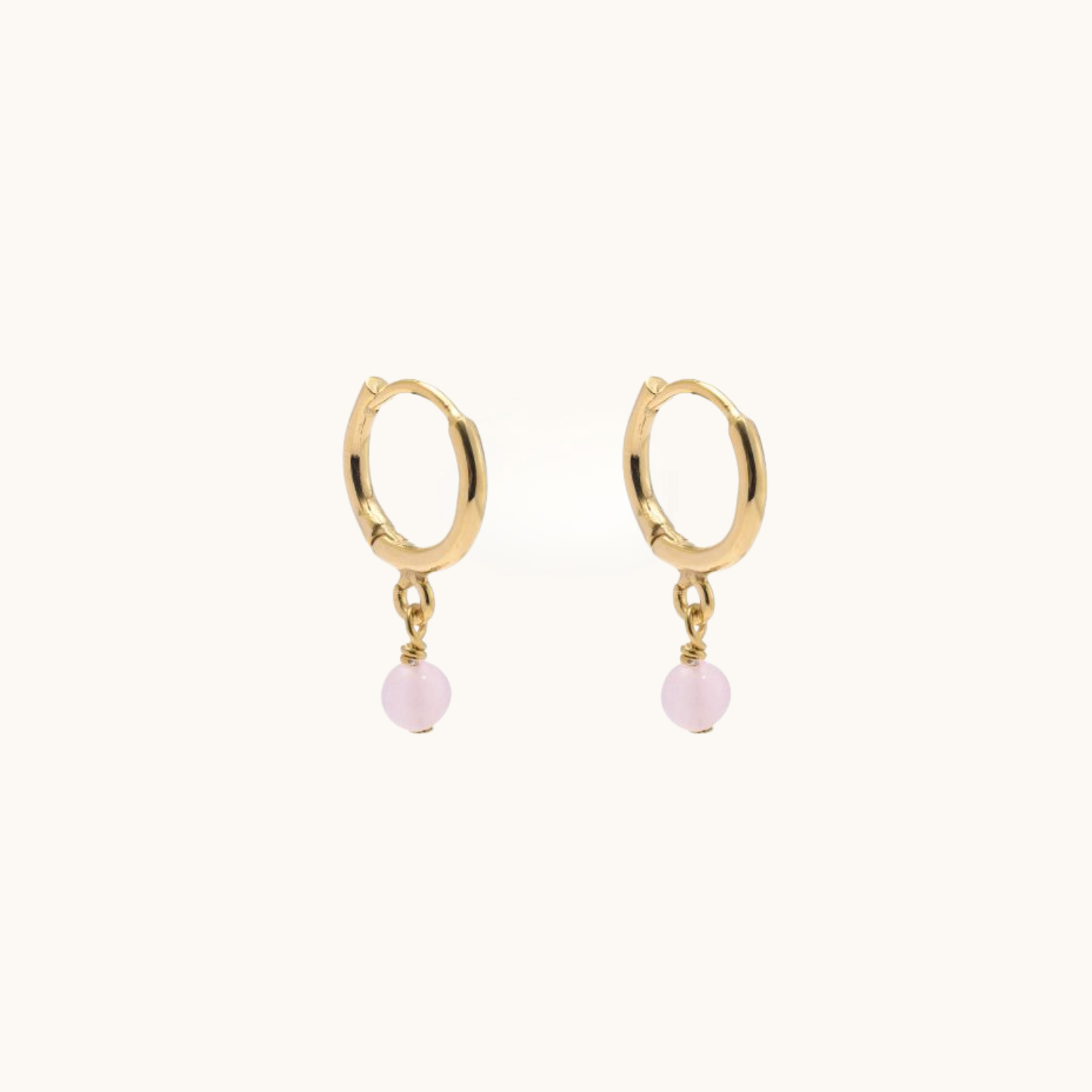 Gold hoop earrings with rose quartz on a white background