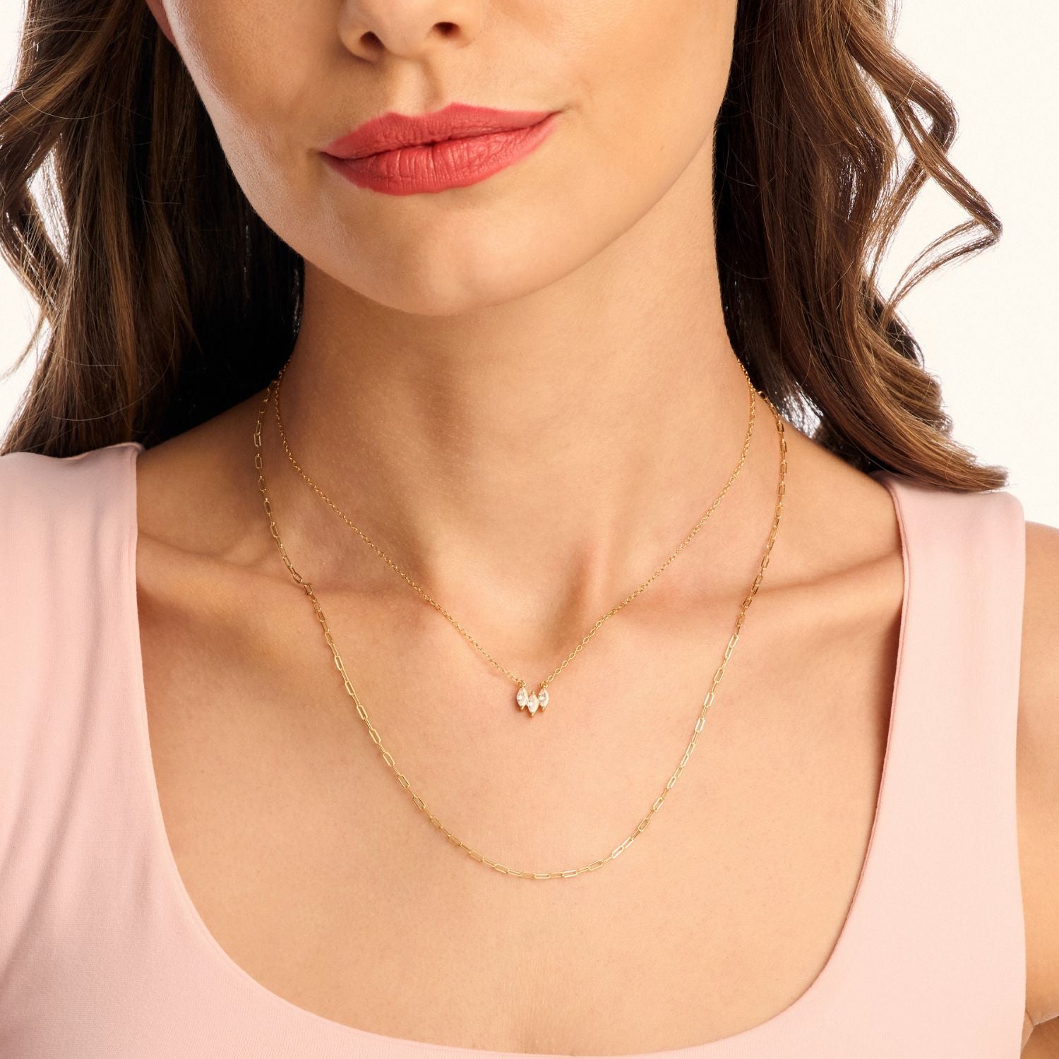 Model wearing a long gold paperclip necklace layered with a shorter necklace, showcasing a chic, modern, and stylish stacked look